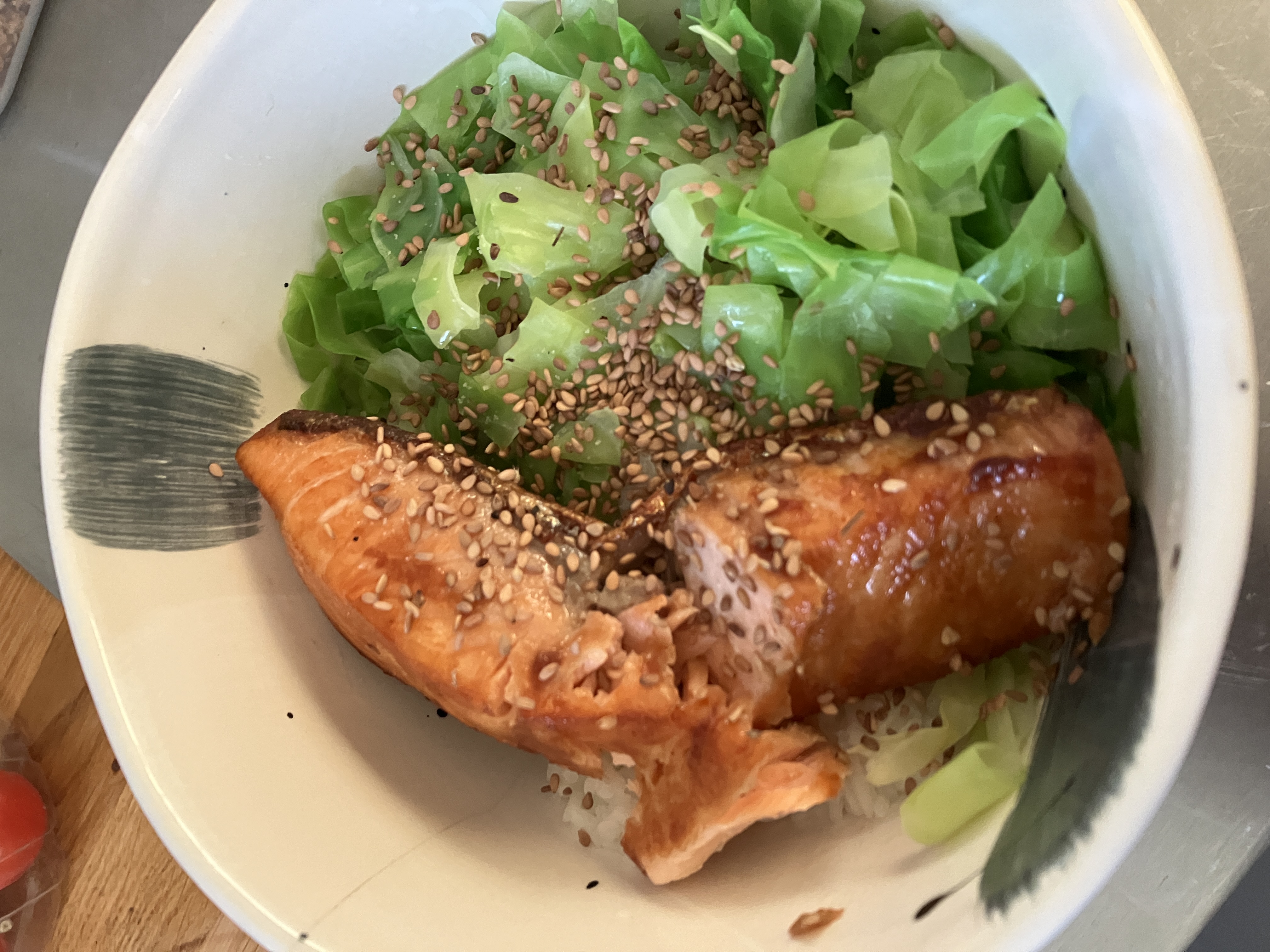 fried salmon and steamed cabbage over rice in a bowl, there are sesame seeds sprinkled on top fried salmon and steamed cabbage over rice in a bowl, there are sesame seeds sprinkled on top